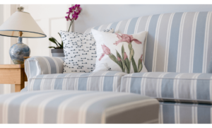 Upholstered blue and cream striped sofa and foot stall