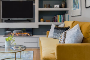 mustard settee with multiple textured cushions in front of a modern entertainment entertainment unit