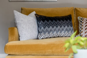 textured black, blue and white cushions on a comfortable mustard sofa